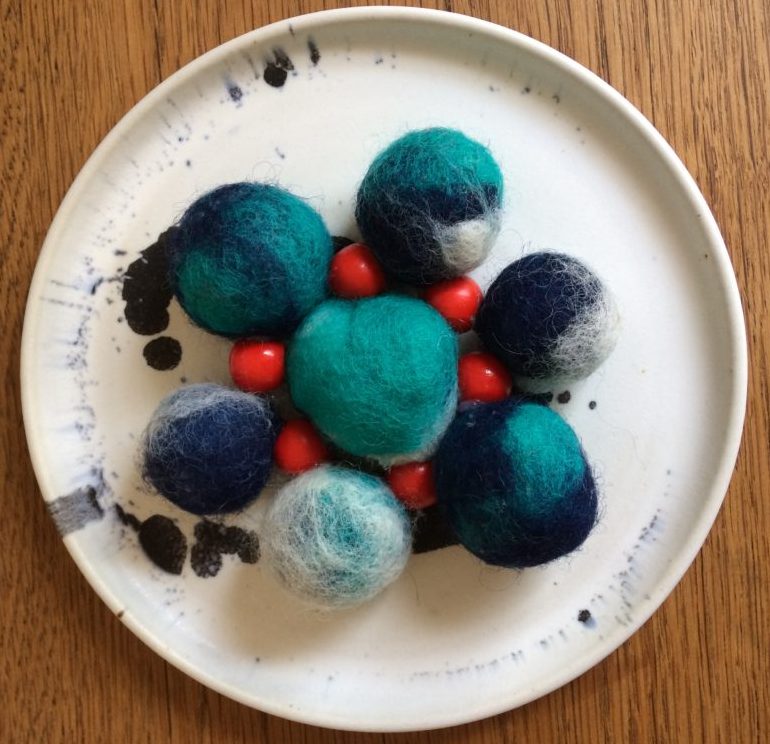 Bordskåner lavet af blå filt bolde og røde perler