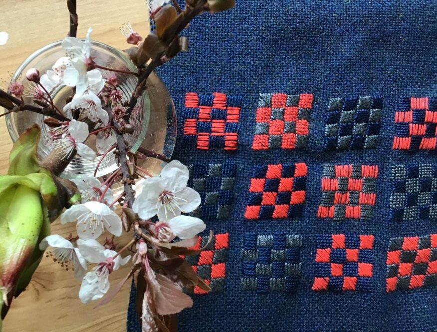 Embroidery on blue wool fabric which will be made into a bag